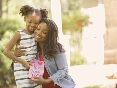 Happy Mother’s Day. Girl gives card to mother.
