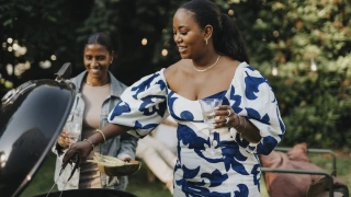 Mid adult woman barbecuing with female family member for garden party
