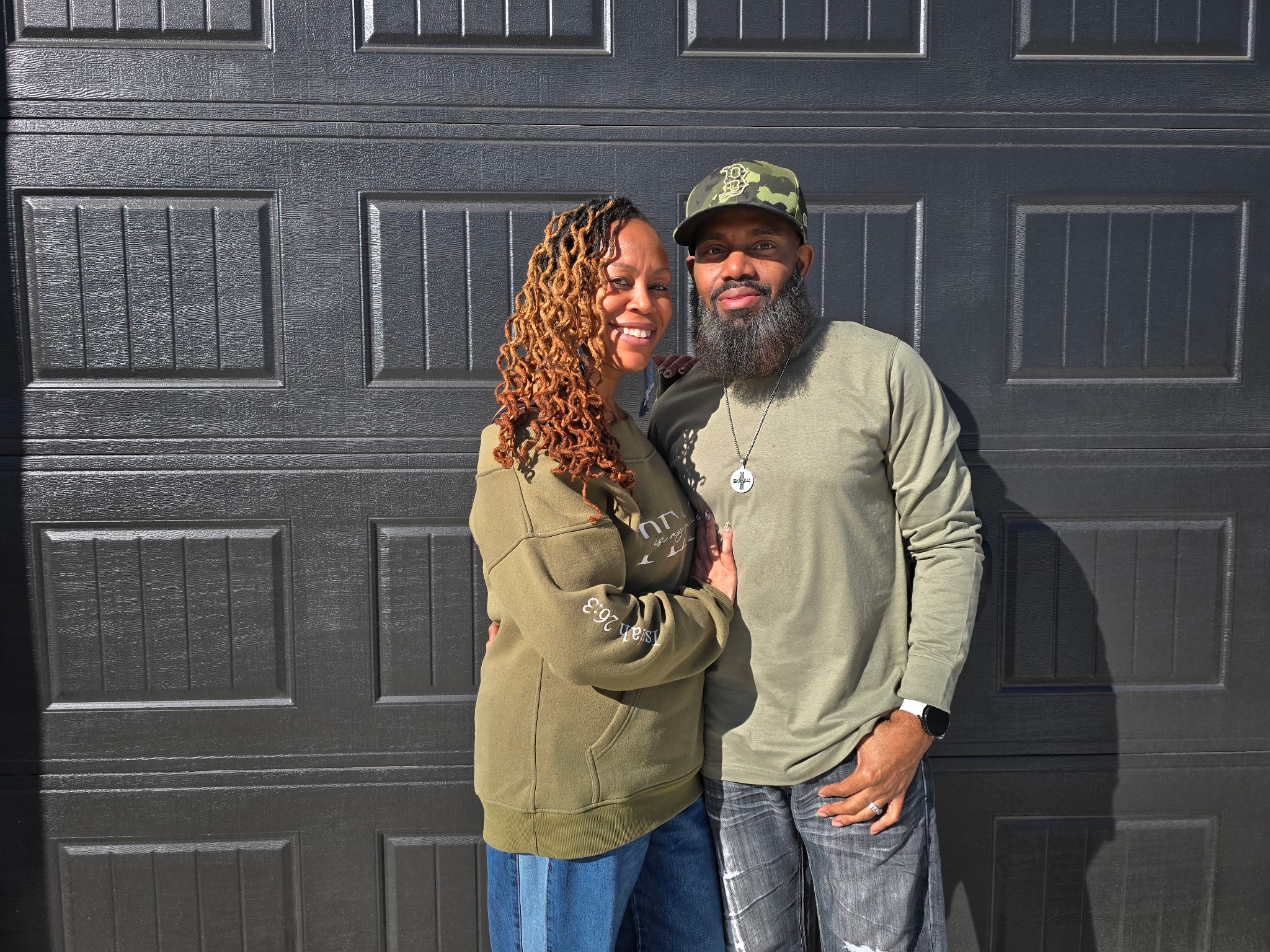A couple poses in front of their home.